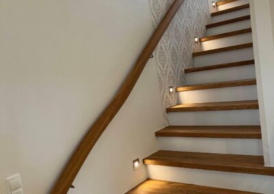 Treppenlauf mit Holzstufen, Wandhandlauf und LED-Stufenbeleuchtung
