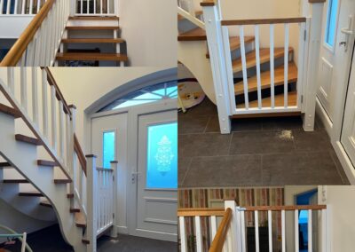 Holztreppe mit weißen Geländern und massiven Eichenstufen in modernem Eingangsbereich