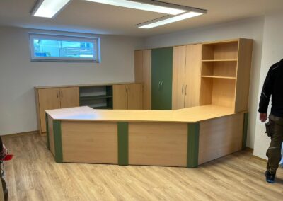 Große Tresenanlage aus Holz mit grünen Akzenten und integrierten Schränken und Regalen