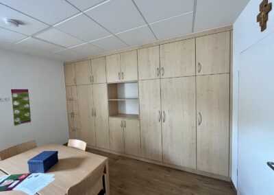 Große Einbauschrankwand aus hellem Holzdekor in einem Gruppen- oder Aufenthaltsraum