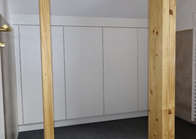 Weißer, maßgefertigter Einbauschrank unter einer Dachschräge in einem modernen Badezimmer