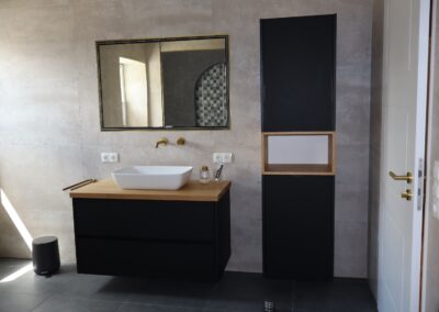 Schwarzer Waschtisch mit Aufsatzwaschbecken und passendem Hochschrank in modernem Badezimmer